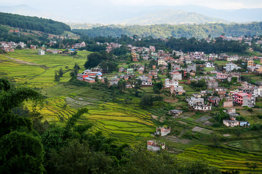 Blick auf den Stadtrand von der Hauptstadt Katmandu in Nepal von oben mit wenigen einfachen Häusern und Reis Terrassen Feldern dazwischen, Landwirtschaft und urbane Strukturen nebeneinander, Asien
