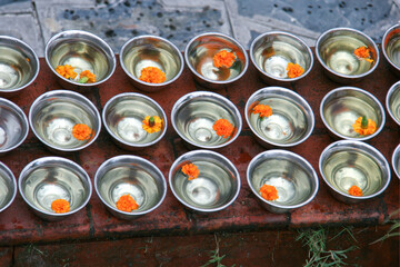 silberne Schalen mit heiligem Wasser mit einer orangen Blüte darin im Affentempel Swayambhunath...