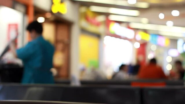 Restaurant staff members are cleaning. Cleaning in a fast food cafe of a shopping center. Defocused blurred bokeh background. Woman clears dishes from tables and puts them in cart