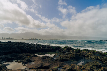 beautiful beach with black rocks on a stormy day on oahu in hawaii