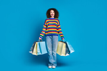 Full body photo of pretty young girl look up empty space shopper dressed stylish rainbow print outfit isolated on blue color background