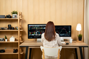 Rear view of white woman at office checking stock market business on computer - 726435989