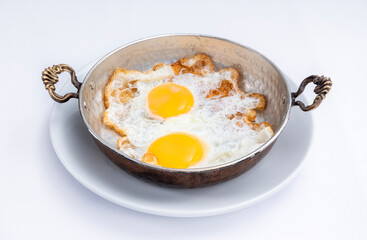 Fried eggs in a copper pan isolated on white background.