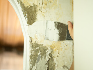 girl applies putty to the wall with a spatula, renovation in the apartment