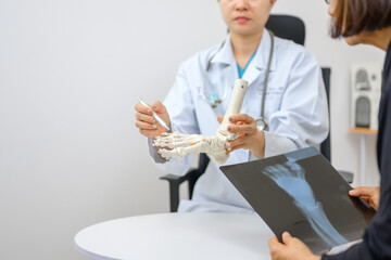 Asian female orthopedist Pointing to the ankle and foot bone model is explaining the patient's foot...