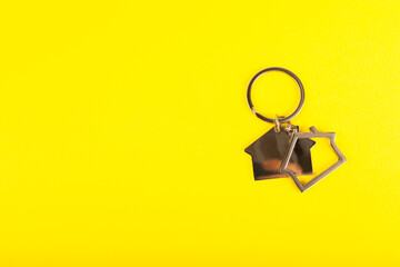 Keychain in the shape of a house with a key ring on background. Concepts for real estate and moving...