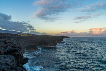 full moon during sunset over the cliffs of the volcanos on the coast of the pacific on big island...