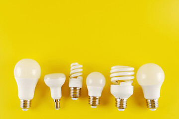 Six new or burnt-out different shapes of electric incandescent lamps in matte white on a yellow...