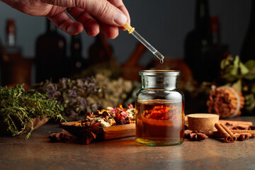 Dropping essential herbal tincture into a small glass bottle.