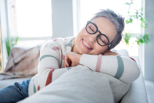 Photo of dreamy pretty woman dressed striped sweater eyewear lying couch sleeping indoors house home room