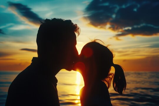 A romantic moment captured as a man and a woman share a passionate kiss against the backdrop of a breathtaking sunset. Perfect for expressing love and affection in various creative projects