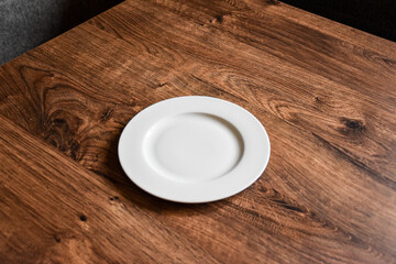 Ceramic white flat plate for food on wooden table top view