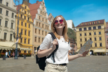 Woman with city map and smart phone. Fantastic view of the ancient homes on a sunny day. Gorgeous and picturesque scene. Location famous Market Square in Wroclaw, Poland, Europe. Historical capital of