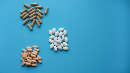 Pills of different colors and shapes on a blue background.