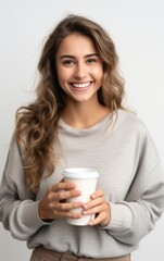Portrait of a pretty cheerful casual girl standing isolated over white background, drinking takeaway coffee.