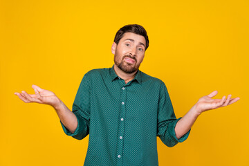 Photo of clueless man with stylish haircut dressed dotted shirt shrugging shoulders have no idea...