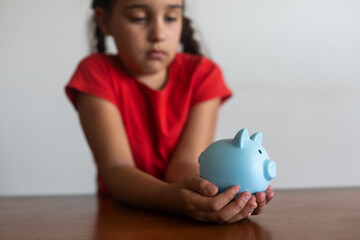 Little girl saving money in a piggybank over a white background