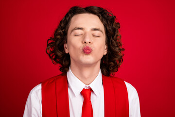 Close up portrait of young handsome guy teenager in formal suit vest and necktie plump lips wanna kisses isolated on red color background - obrazy, fototapety, plakaty