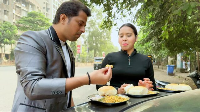 young couple eating roadside food on the car dicky