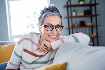 Photo of dreamy pretty woman dressed striped sweater eyewear sitting couch relaxing indoors house...
