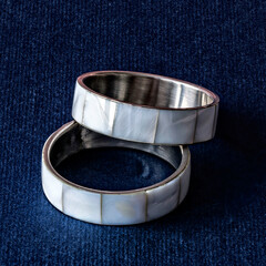 Silver rings with mother-of-pearl on a dark blue background.