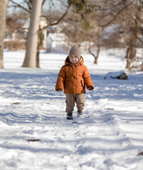 Fototapeta na wymiar Portrait of two year old boy standing in fresh snow in winter playing outdoors