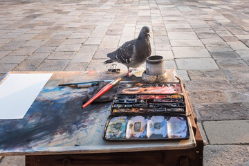 Artist's palette, paints, brushes and a dove that helps the artist