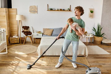 happy man multitasking housework and childcare, father vacuuming bedroom with infant boy in arms - obrazy, fototapety, plakaty
