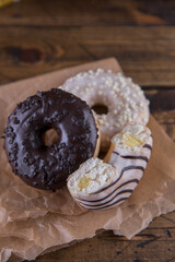 Several donuts on baking paper on a wooden background.