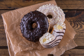 Several donuts on baking paper on a wooden background.