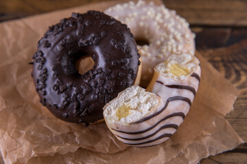 Several donuts on baking paper on a wooden background.