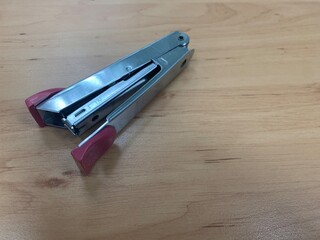 Paper stapler with pink handle on wooden table, office stationary	