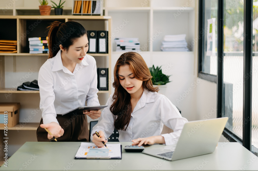 Wall mural two asian businesswoman discuss investment project working and planning strategy with tablet laptop 