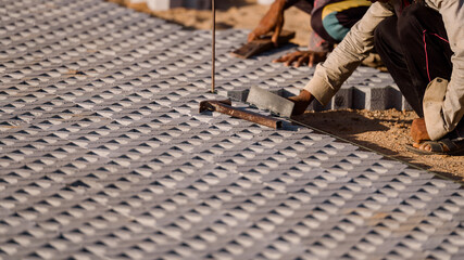 Installing paving blocks concept. Diligent man engages in outdoor construction work, laboriously...