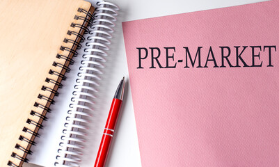 PRE-MARKET word on the pink paper with office tools on white background