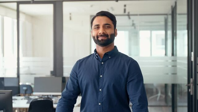 Happy confident Indian businessman professional leader wearing blue shirt standing arms crossed in office. Smiling business man company executive manager worker, eastern entrepreneur at work,portrait.