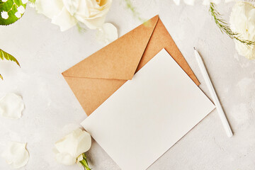 Crafting pastel paper envelope for greetings, invitation, postcard, text among white flowers. Copy space.