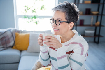 Photo of good mood sweet woman dressed striped sweater eyewear enjoying herbal tea indoors house...