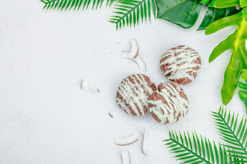 Profiteroles choux pastry buns with coconut cream served in tropical style. Palm leaves