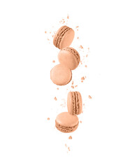 French sweet colorful cookies macarons macaroons with crumbs in trendy color 2024 Peach Fuzz flying isolated on white background with copy space.