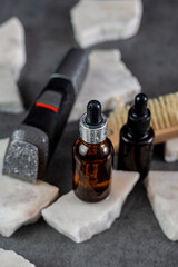 Man beard grooming items on a stone table surface, comb, oil and electric trimmer