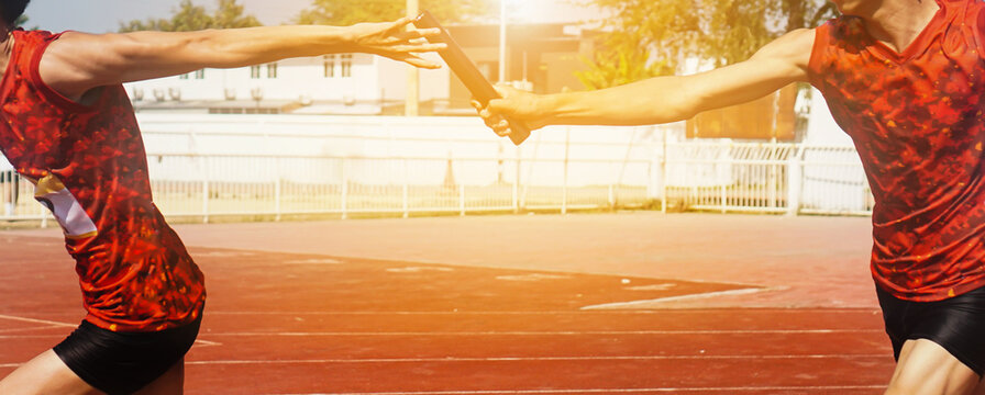 Professional Athlete passing a baton to the partner against race on racetrack.selective focus.