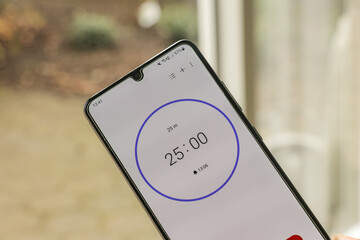 A phone with a black and white 25-minute timer to study with the pomodoro method on a blurry...