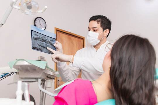 Dentist showing his patient a dental x-ray in the dental office.