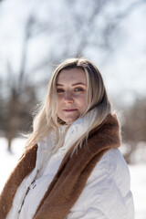 Portrait Cheerful young woman in warm winterwear  having fun in winter forest among trees