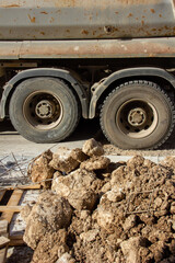 A construction pile of stones and sand against the backdrop of large truck wheels

