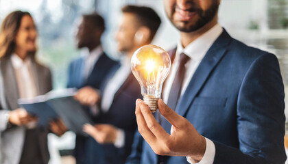 Professional in suit holds glowing Edison light bulb, symbolizing innovation and creativity in business development