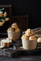 Golden cream puffs in a paper cup with a blurred floral background.