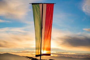 Italian flag hoisted vertically at sunset.