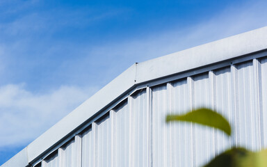 Corrugated steel industrial factory building wall on blue sky with cloud background.